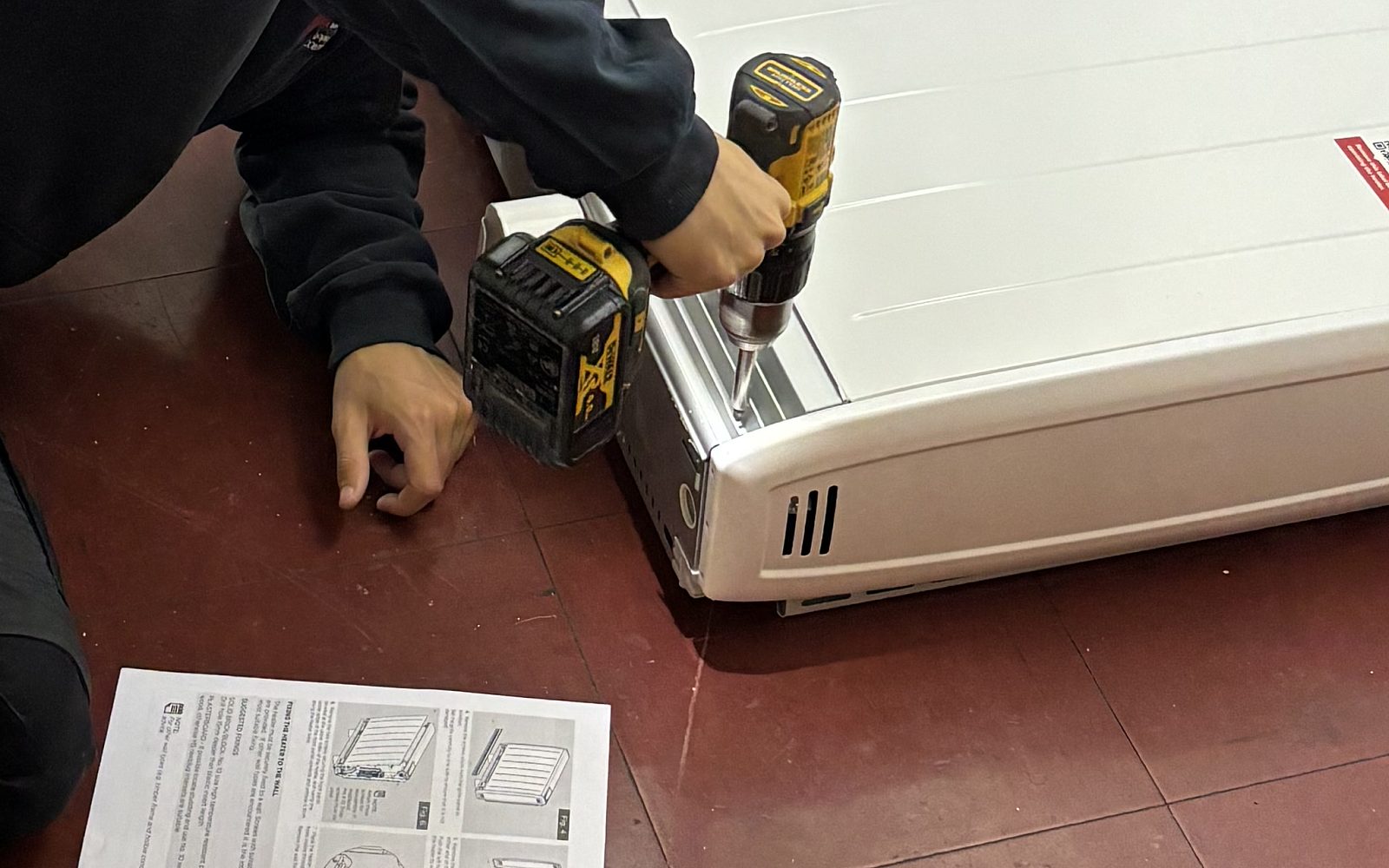 Close view of a new electric heater being fixed with a cordless drill