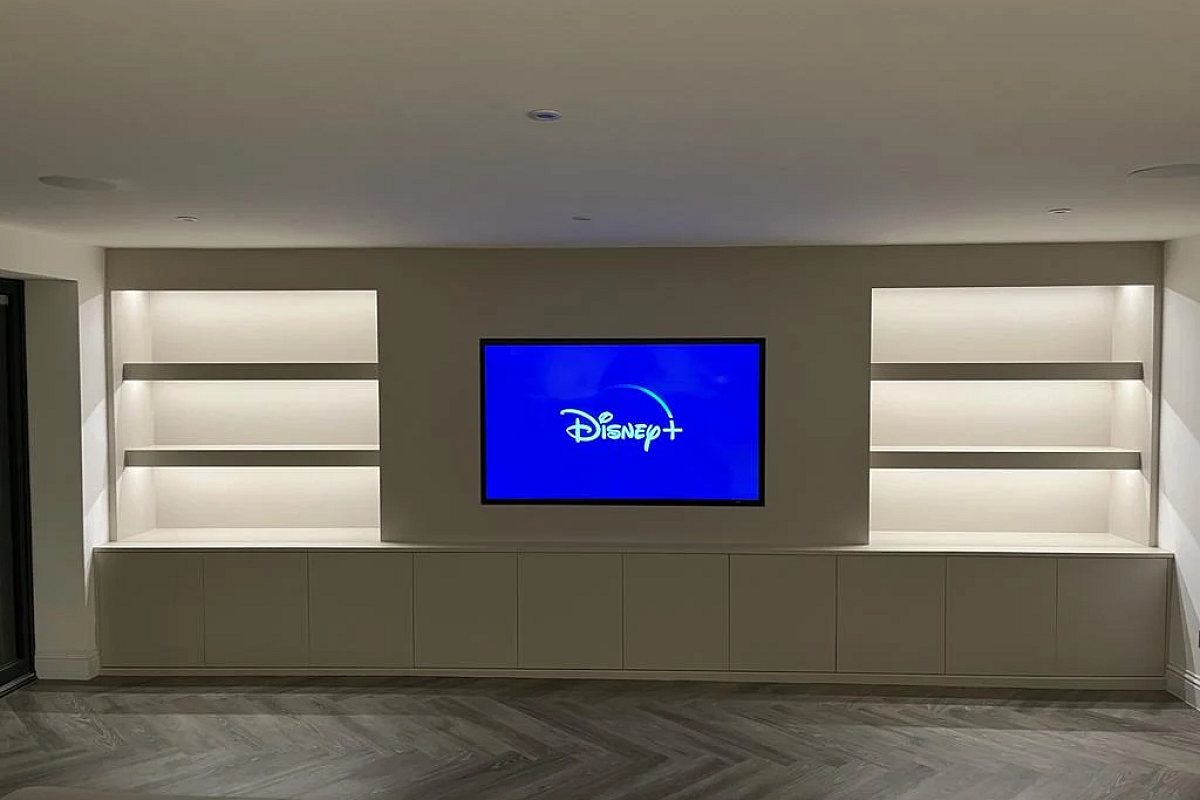 Finished media wall in use, with the LED shelf lighting on and the television running