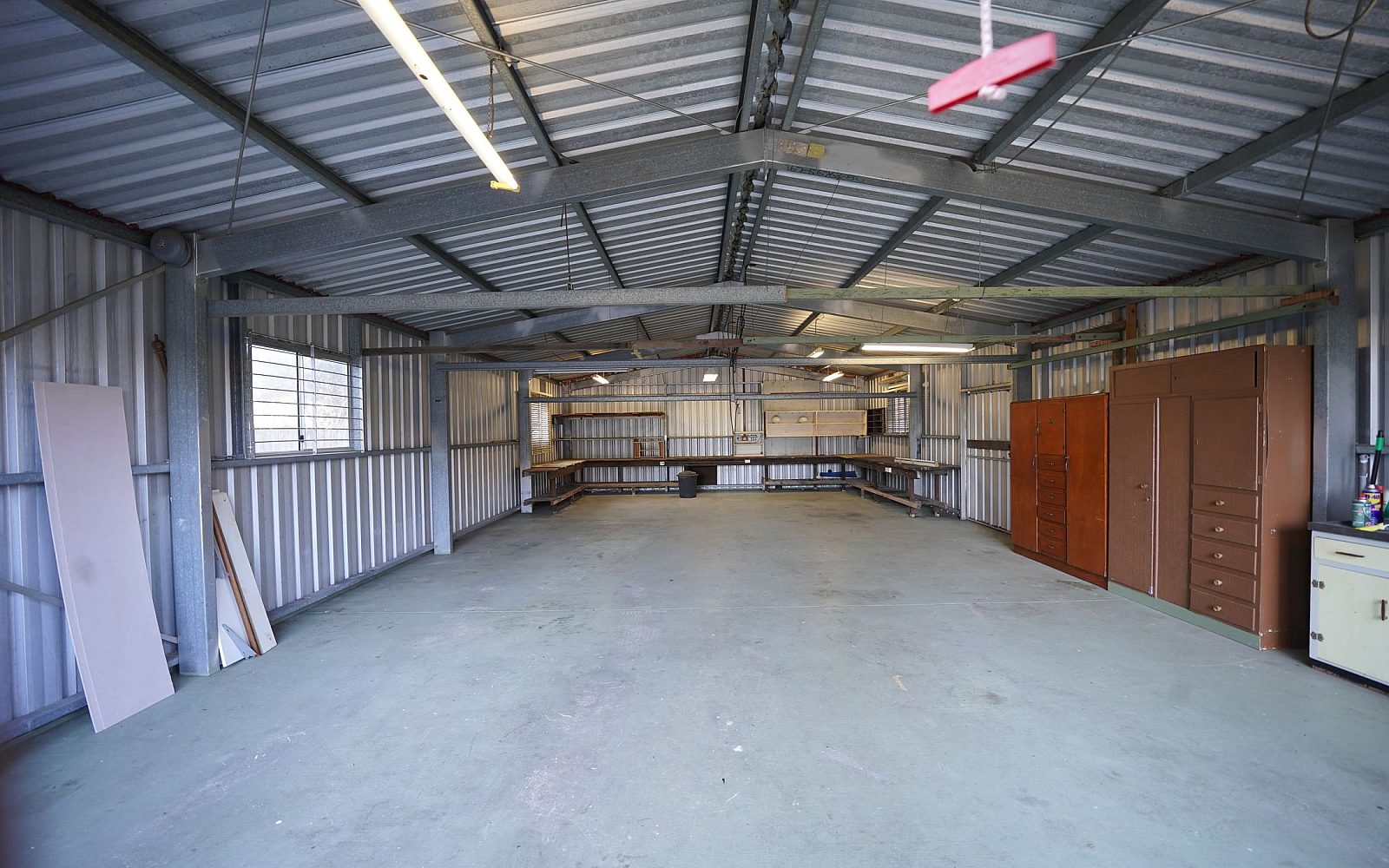 Interior of a storage unit showing steel racking and overhead industrial lighting